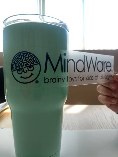 A clear vinyl transfer sticker featuring the MindWare logo. Designed for clean application to cups, glass, laptops, or any smooth surface—great for promotional branding.